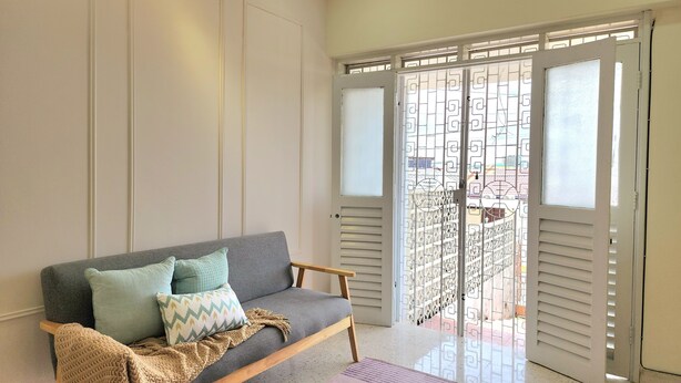 Un salon avec un canapé gris, un plaid à motifs et une chaise en bois.