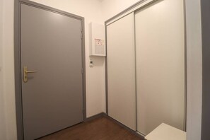 A narrow hallway with a door and a closet, featuring a notice on the wall.