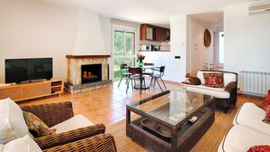 Un salon équipé d’un téléviseur, d’une cheminée, de meubles en osier et d’une table basse en verre.