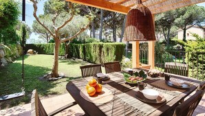 Un espace extérieur aménagé pour les repas, avec une table en bois, des chaises et un luminaire suspendu.