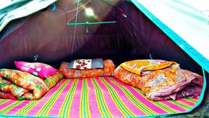 A tent interior with colorful bedding and a striped mat. - Shri Narayan Tourist Lodge (Ukhimath)
