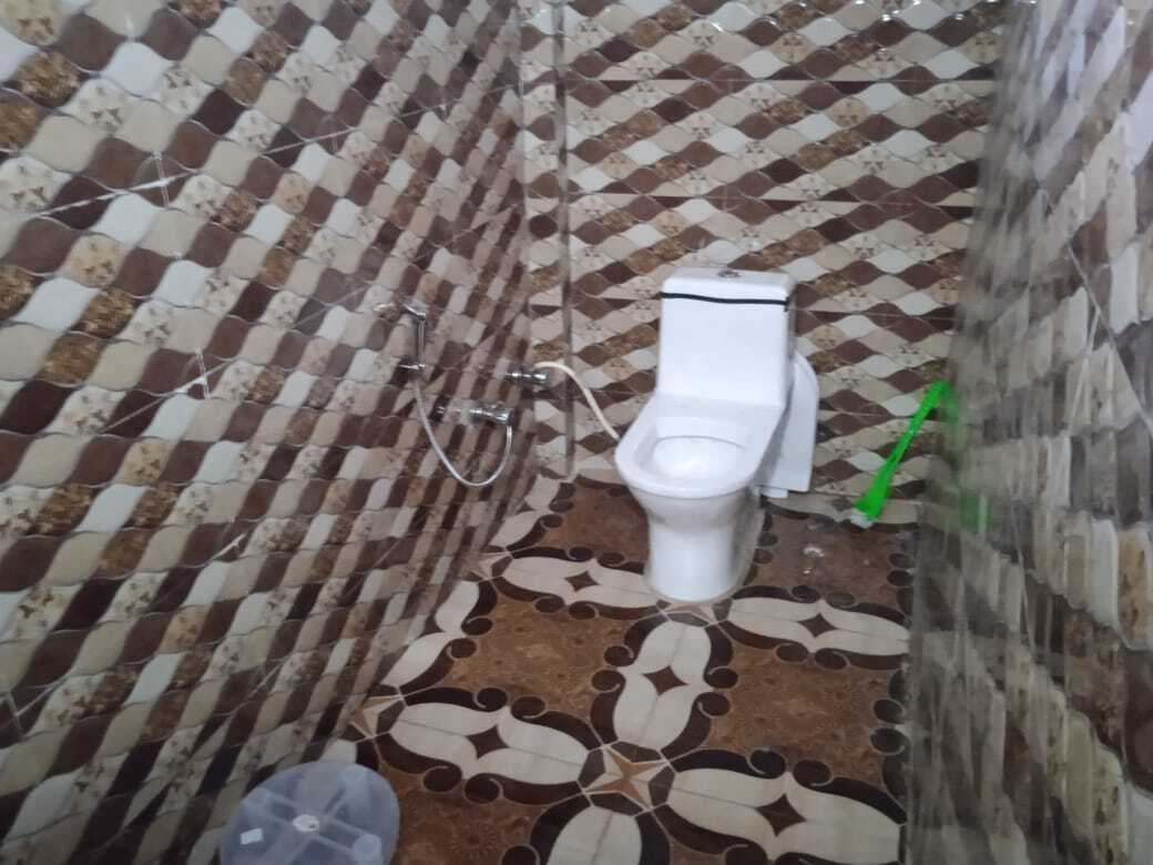 A bathroom with a patterned floor, a toilet, and a shower area.