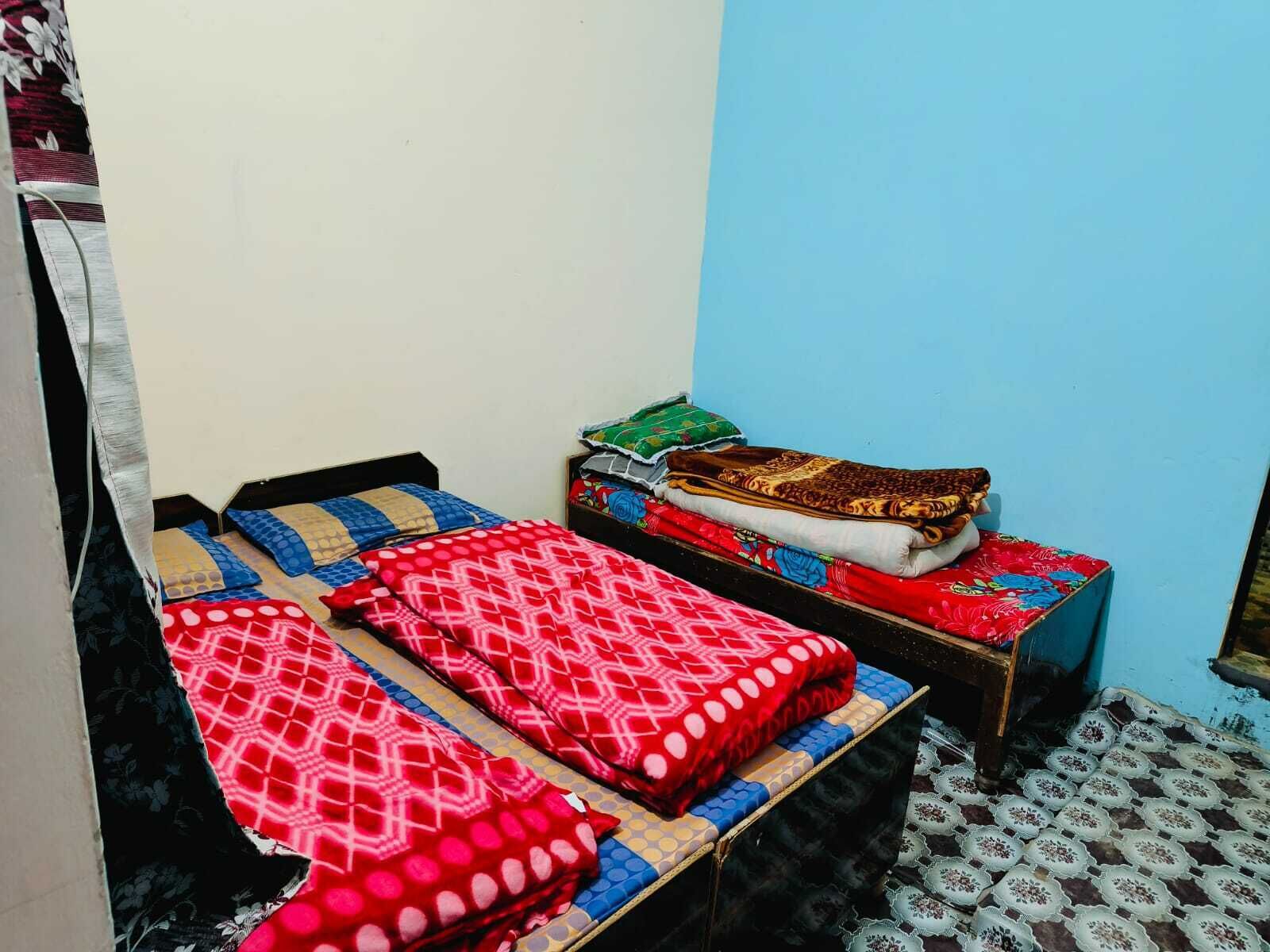 A small, single-room accommodation with a bed, a small table, and a chair.