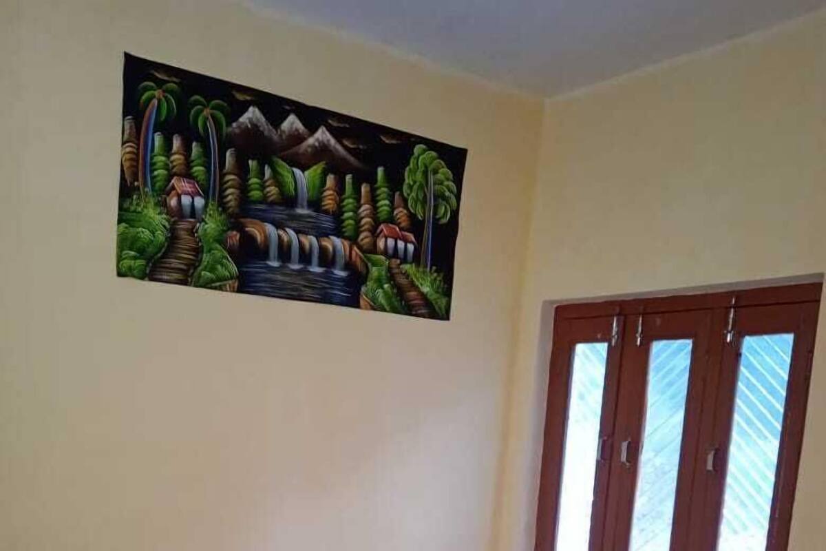 Une pièce avec un lit, une fenêtre avec des rideaux et un tableau au mur.