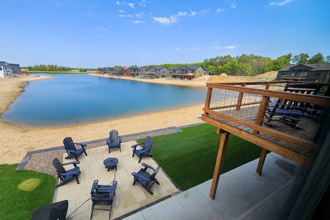 A deck with outdoor seating overlooking a lake and beach.