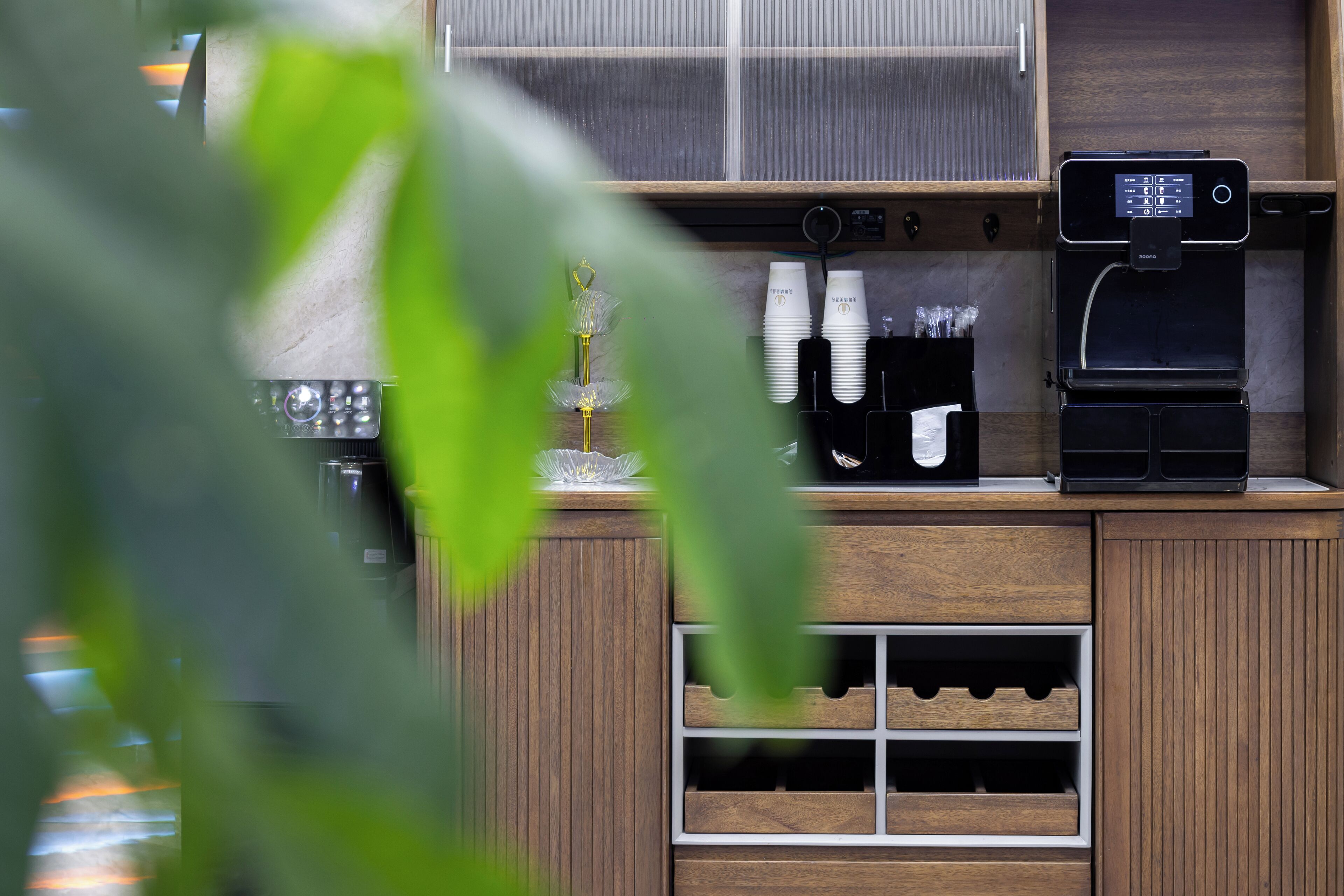 A coffee station with a coffee machine, cups, and a wine cooler.