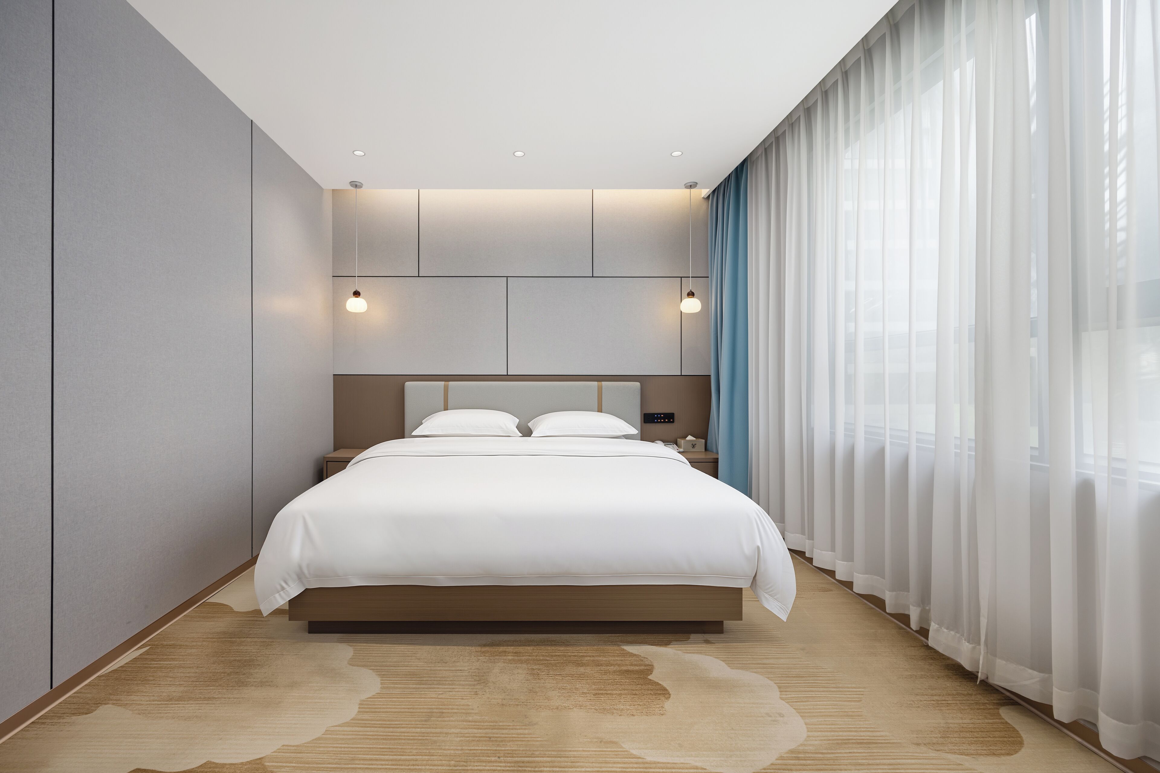 A modern bedroom with a large bed, a nightstand, and a wall-mounted light fixture.