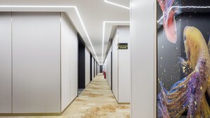 A hallway with a patterned carpet, white walls, and a directional sign. - Meihao Exquisite Hotel (Guangzhou)