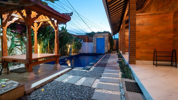 A pool area with a wooden pergola, a blue door, and a pathway with stepping stones. - Comfortable Private Room in Canggu with High-speed WiFi (Bali)