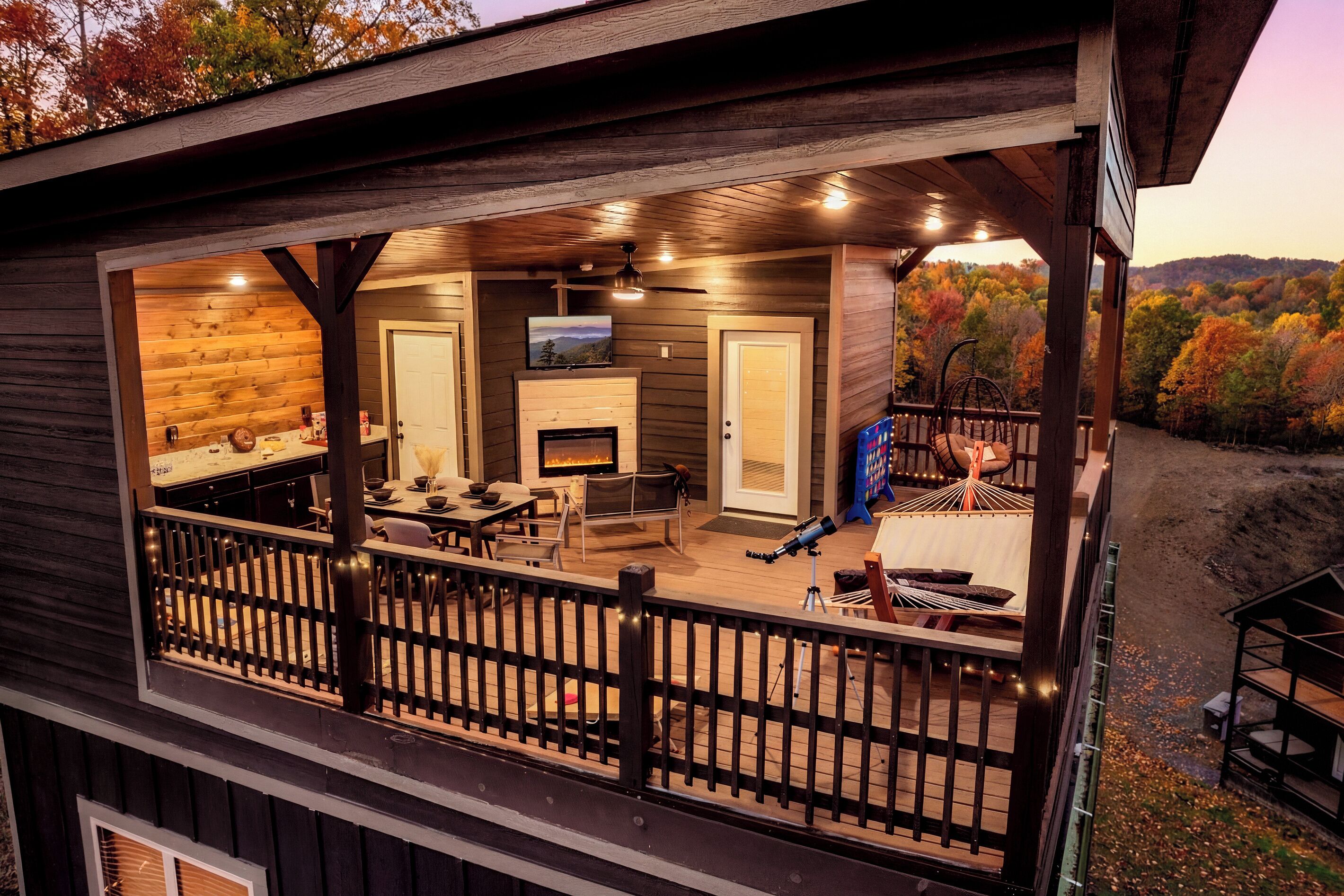 Una terraza de madera con chimenea, zona de estar y televisor.