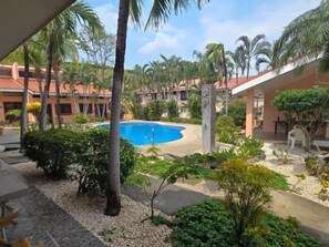 Una piscina rodeada de palmeras y vegetación, con edificios al fondo.