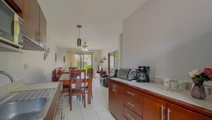 A modern kitchen with a dining area, featuring a sink, cabinets, and a coffee maker.