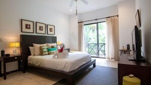 A hotel room with a bed, a desk, a chair, a TV, and a window with curtains.
