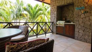 A balcony with wicker furniture, a stone wall, and a sign reading 'Beach'.