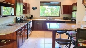 Una cocina con armarios de madera, un ventanal grande y un taburete de bar.