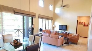 Amplia sala de estar con una mesa de vidrio, dos sofás y un televisor.