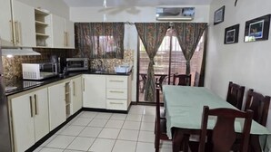 A compact kitchen with a dining area, a ceiling fan, and an air conditioning unit. - Cormoran A2 2 bed 2 Bath Condo In las Palmas (Playas del Coco)