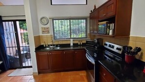 Una cocina con armarios de madera, estufa y ventana con persianas.