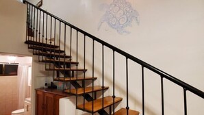 Una escalera con escalones de madera y barandas de metal negro, que conduce a un piso superior.