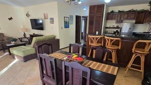 A dining area with a table, chairs, and a kitchen in the background. - Vista Hermosa D2 2 bed 2 bath Spacious & Fully Equipped Condo (Playa Hermosa)