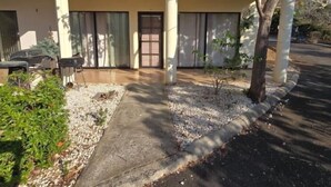 A building with a beige facade, large windows, and a small garden area with a tree and gravel path. - Vista Hermosa D2 2 bed 2 bath Spacious & Fully Equipped Condo (Playa Hermosa)