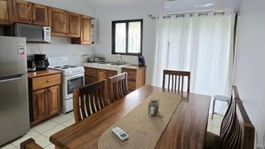 A compact kitchen with wooden cabinets, a microwave, a stove, and a sink. - Green Life #3 | Perfect Beachside Living (Playas del Coco)