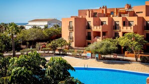 Un edificio moderno con varios balcones, piscina y vista al mar.