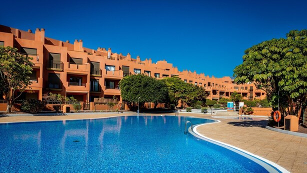 Una piscina amplia y despejada rodeada de edificios color naranja con balcones.