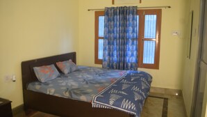 A bedroom with a bed, a window with curtains, and a door. - Amrit Palace (Faizabad)