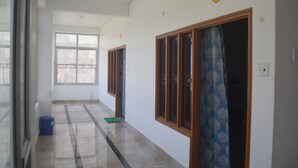 A hallway with a number 2 sign, a blue trash bin, and a green mat on the floor. - Amrit Palace (Faizabad)