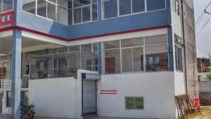 A two-story building with a flat roof, large windows, and a sign indicating a specific location. - Amrit Palace (Faizabad)