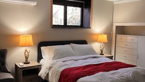 A bedroom with a bed, two bedside tables with lamps, a chair, a window, and a wardrobe.
