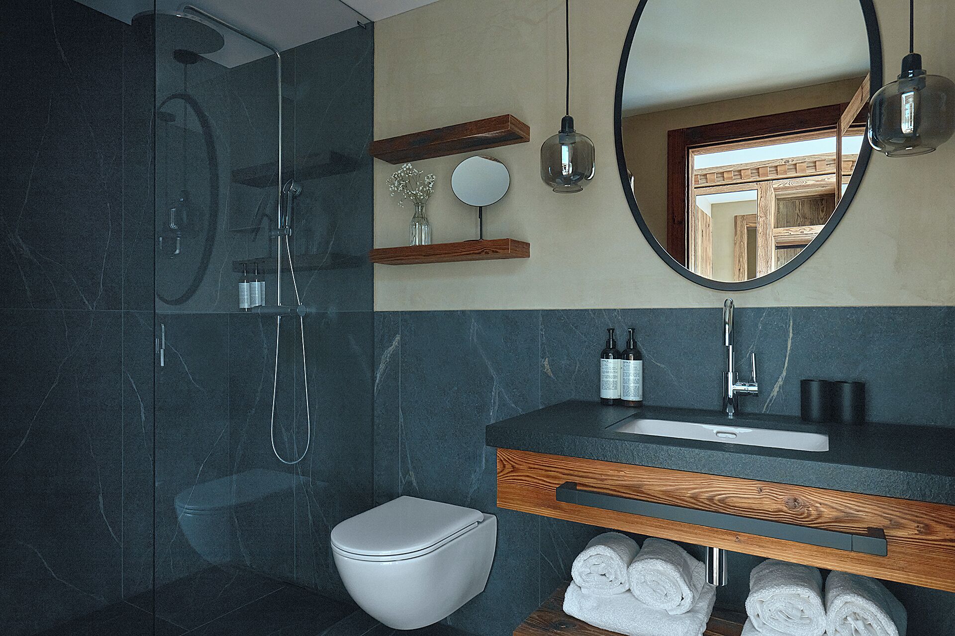 A modern bathroom with a glass-enclosed shower, a white toilet, a wooden vanity with a sink, and a mirror above the vanity.