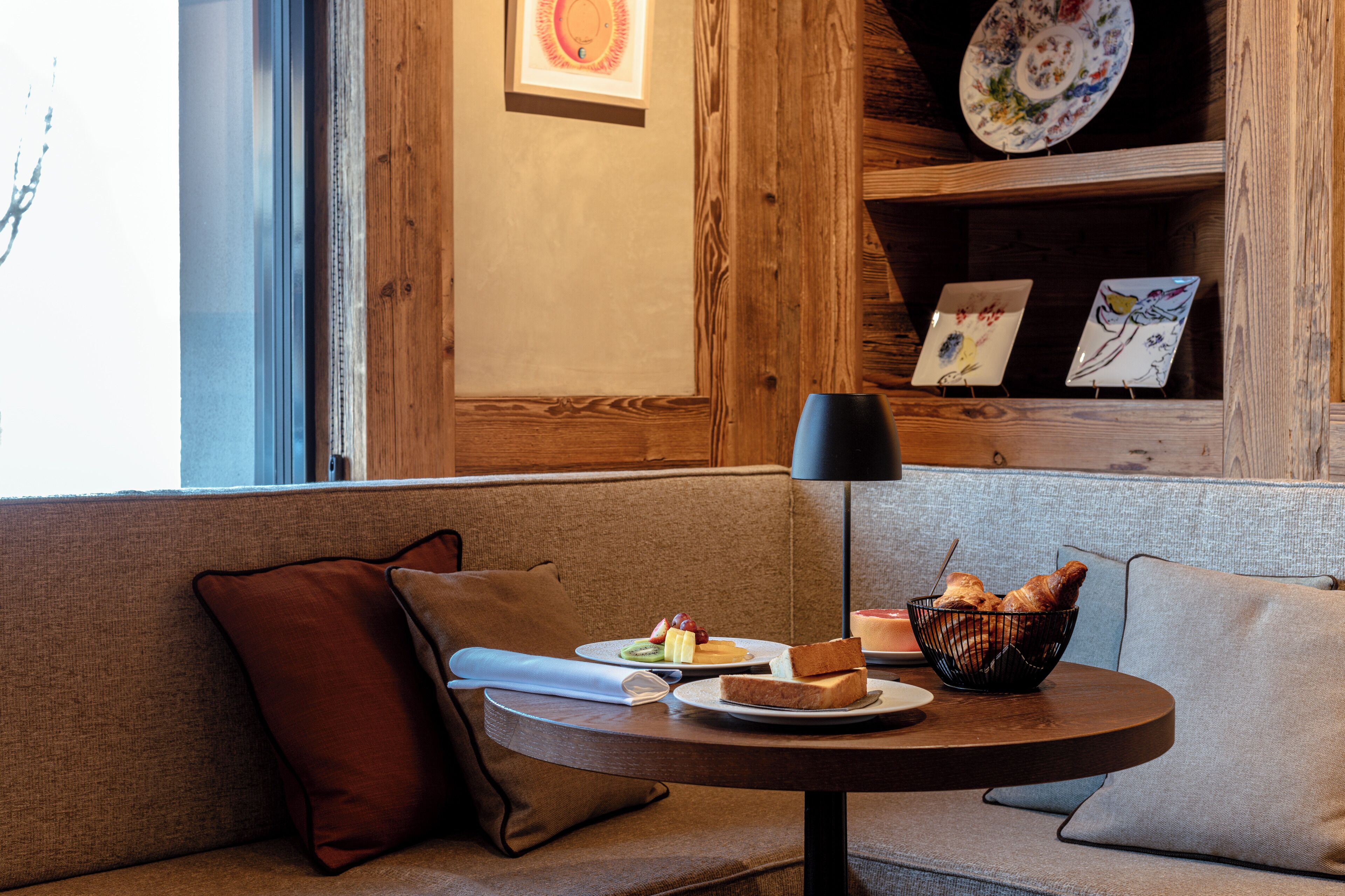 A cozy seating area with a round table, a basket of bread, and a plate of food.