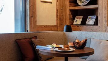A cozy seating area with a round table, a basket of bread, and a plate of food.