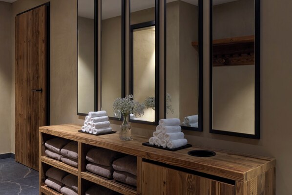 A wooden vanity with towels and a vase of flowers. - Miiro The Mansard (Saanen)
