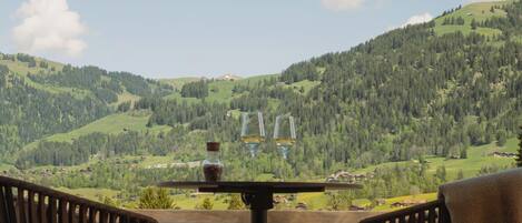 A terrace with two chairs and a table, overlooking a mountainous landscape.