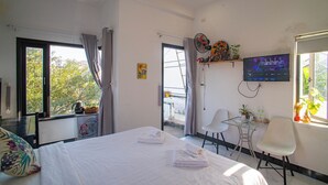 A modern hotel room with a large bed, a TV, a balcony, and a small table with chairs. - Sophia Homestay Hoi An (Da Nang)