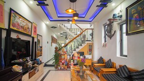 A modern living room with a TV, sofa, and a staircase leading to an upper level. - Sophia Homestay Hoi An (Da Nang)