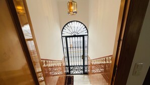 A staircase leading to a gated entrance with a decorative railing and a hanging light fixture.