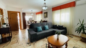 A living room with a sofa, a coffee table, and a dining area in the background.