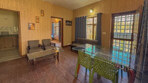 Una habitación con pared de paneles de madera, una mesa de vidrio con sillas, un sofá y una puerta con ventanal.