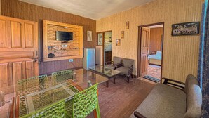 Un espacio habitable compacto con cocina, zona de estar con mesa de vidrio y puerta que da a un dormitorio.