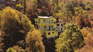 Un edificio amarillo de varios pisos rodeado de un bosque frondoso.