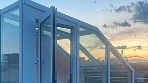 A modern glass-enclosed structure with a metal frame, likely a conservatory or greenhouse, on a rooftop with a wooden deck. - DREAM 360° City Skyline Rooftop Terrace & Balcony (Wien)