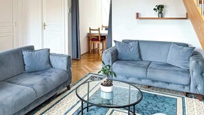 A modern living room with two grey sofas, a glass coffee table, and a staircase with wooden railings. - DREAM 360° City Skyline Rooftop Terrace & Balcony (Wien)