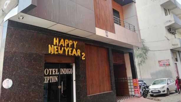 A hotel with a 'Happy New Year' sign, a reception area, and a parked car outside. - Hotel Indigo (Rohtak)