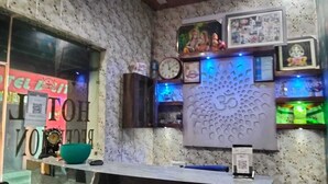 A reception area with a marble wall, a clock, framed pictures, and a decorative wall piece. - Hotel Indigo (Rohtak)