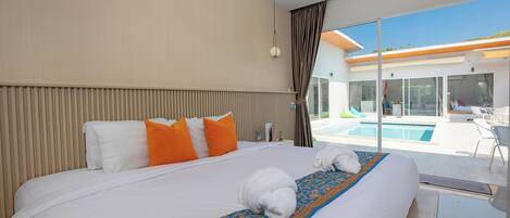 A hotel room with a large bed, a pool view, and a modern design.