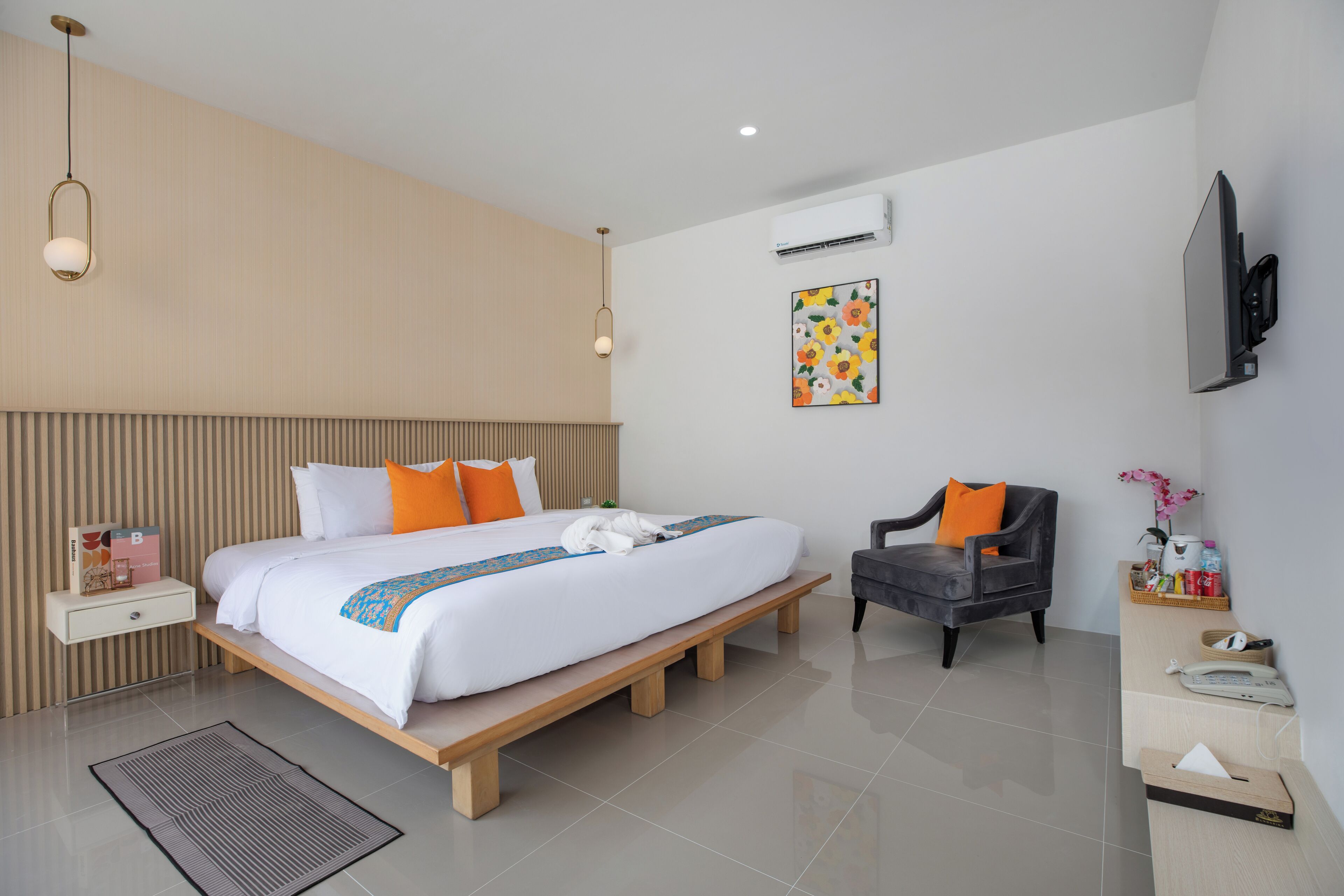 A modern hotel room with a large bed, bedside tables, a chair, a desk, and a TV.